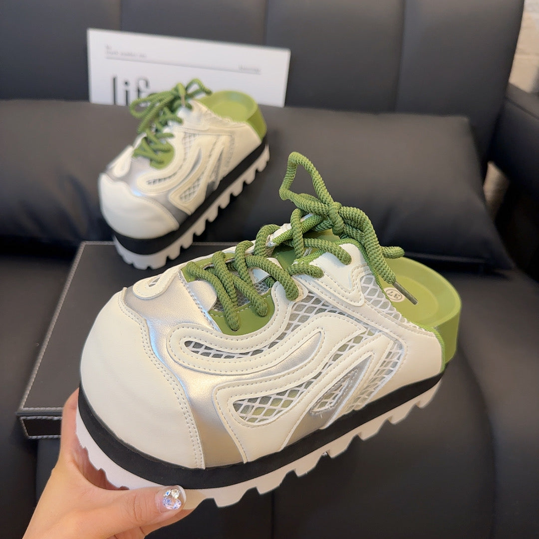 A pair of chunky platform sneakers with a vibrant green jagged sole, a black midsole, and a white and silver upper with yellow laces
