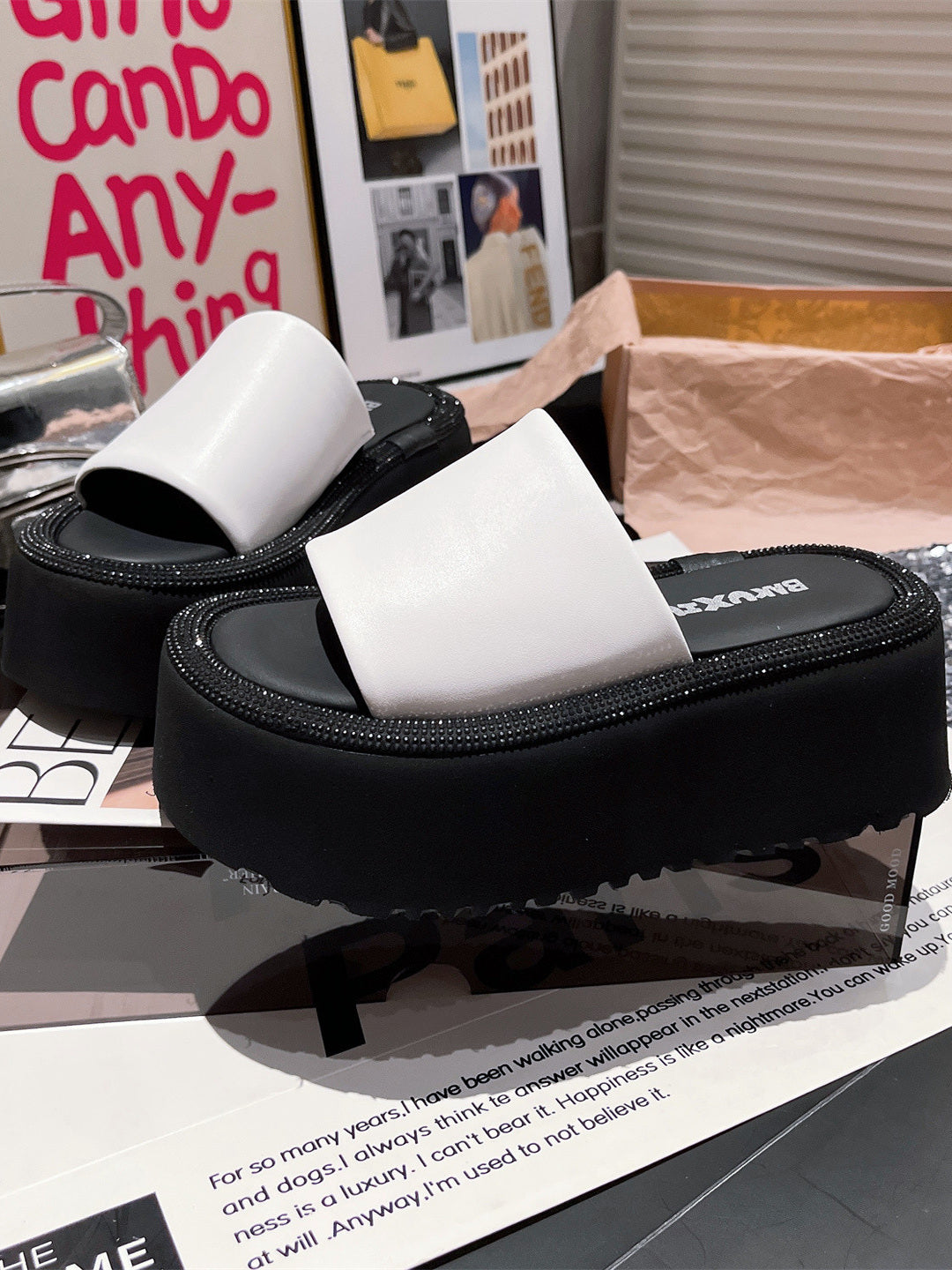 Two pairs of women's platform slides, one black and one white, featuring wide straps and thick black soles