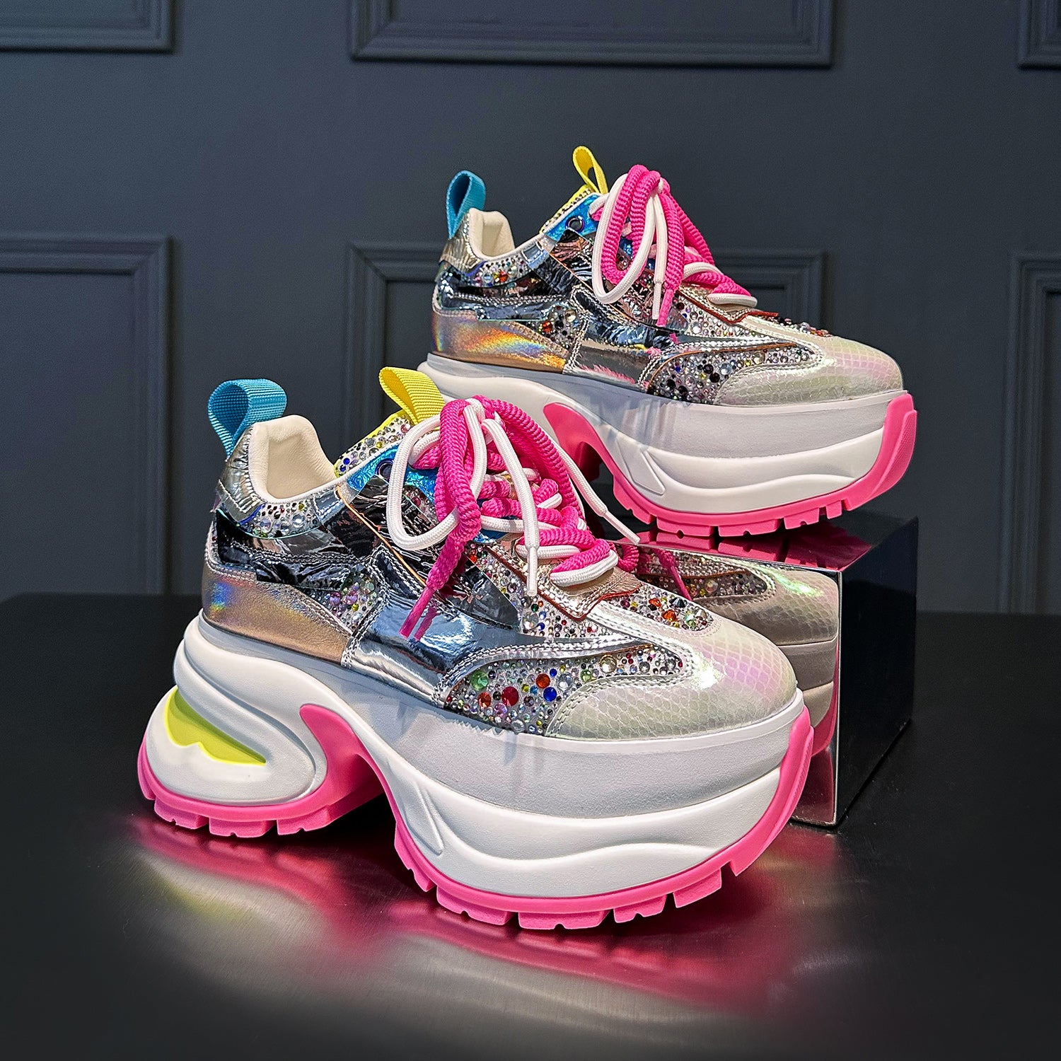 These chunky platform sneakers feature a dazzling holographic silver upper, vibrant pink laces, and a bold white and pink platform sole. Make a statement with these trendy fashion sneakers.Shop now!