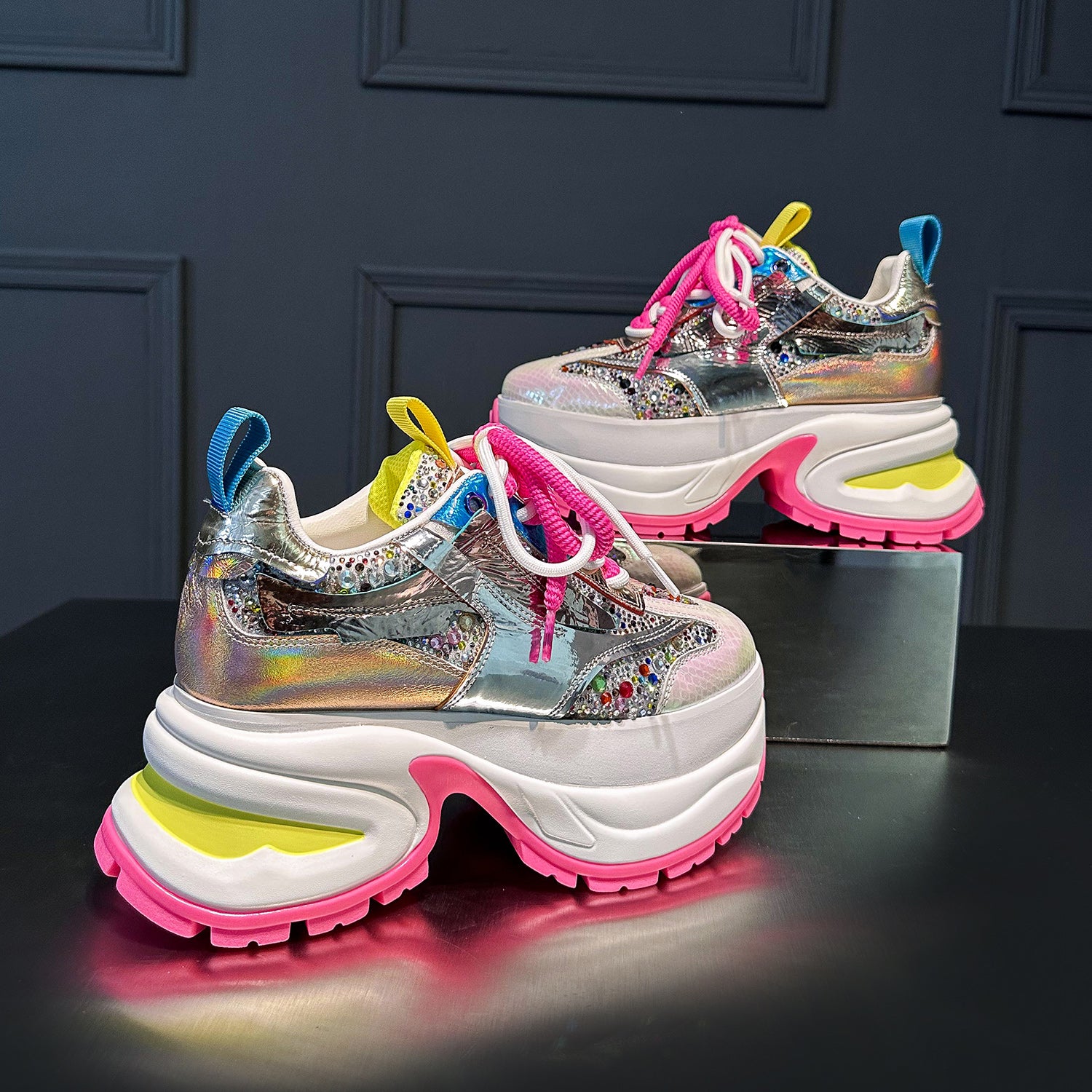 These chunky platform sneakers feature a dazzling holographic silver upper, vibrant pink laces, and a bold white and pink platform sole. Make a statement with these trendy fashion sneakers.Shop now!