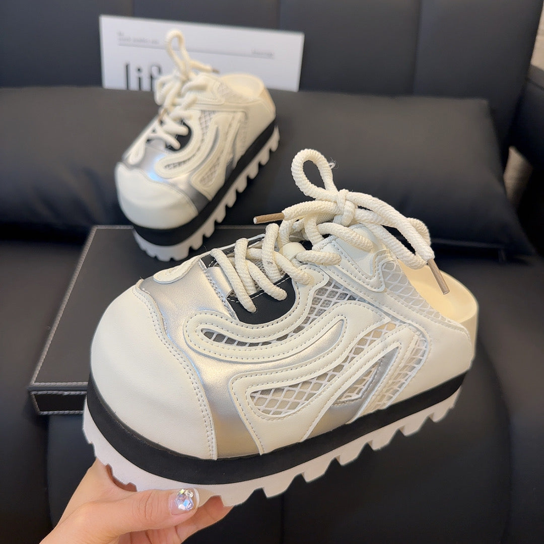 A pair of chunky platform sneakers with a vibrant silver white jagged sole, a black midsole, and a white and silver upper with yellow laces