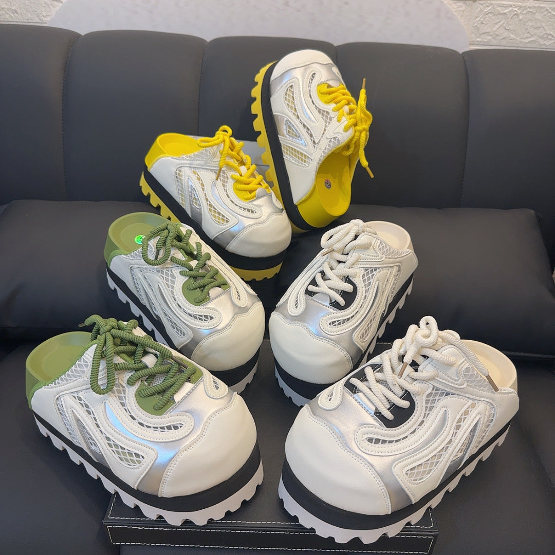 A pair of chunky platform sneakers with a vibrant colors jagged sole, a black midsole, and a white and silver upper with yellow laces