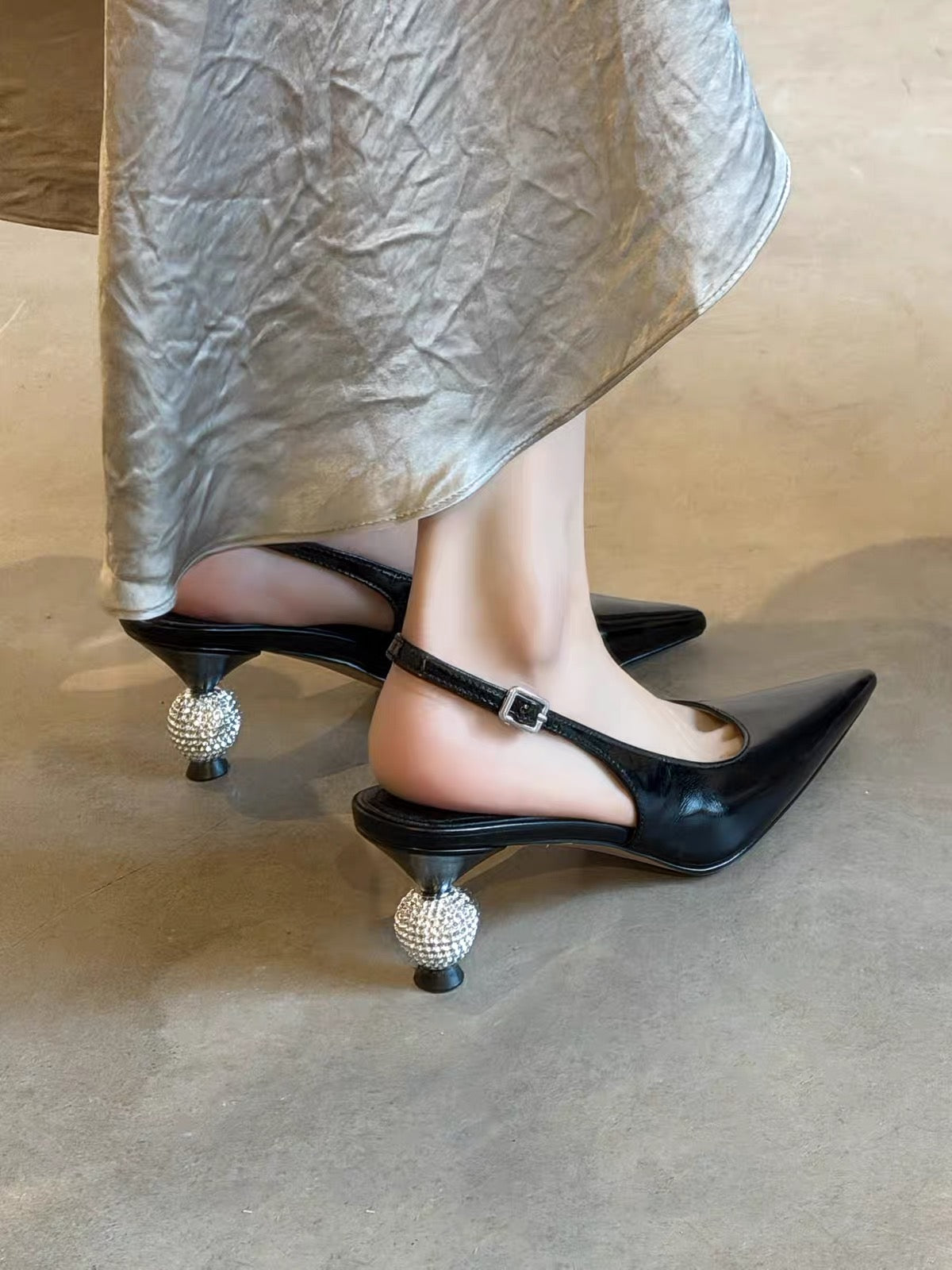 Black pointed-toe slingback shoes with sparkling ball heels