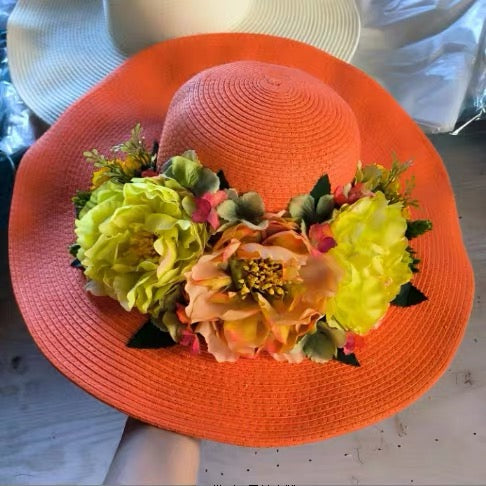 Orange straw sun hat with peach and yellow floral decoration