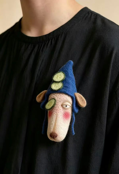 Handmade felt zodiac character brooch wearing a blue hat with cucumber details
