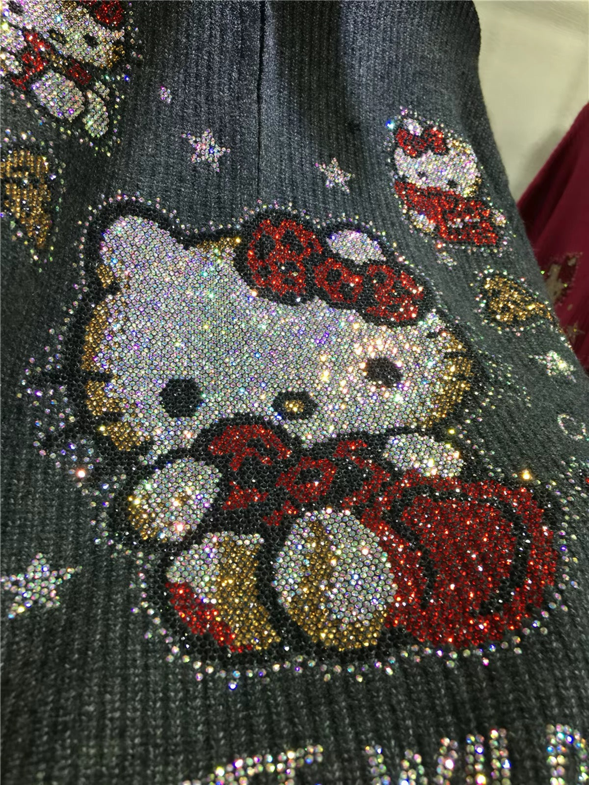 Close-up of multicolour rhinestone character design on black knit sweater