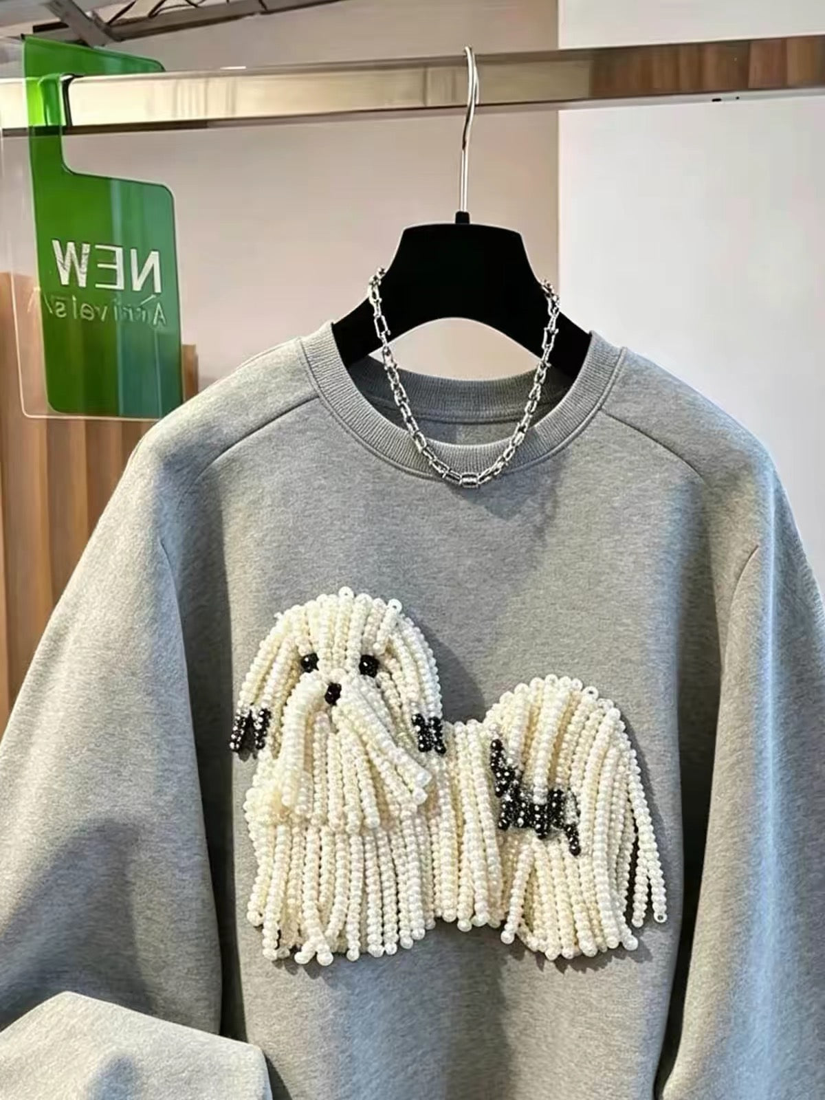 Close-up of the pearl-beaded dog embellishment on the grey sweatshirt