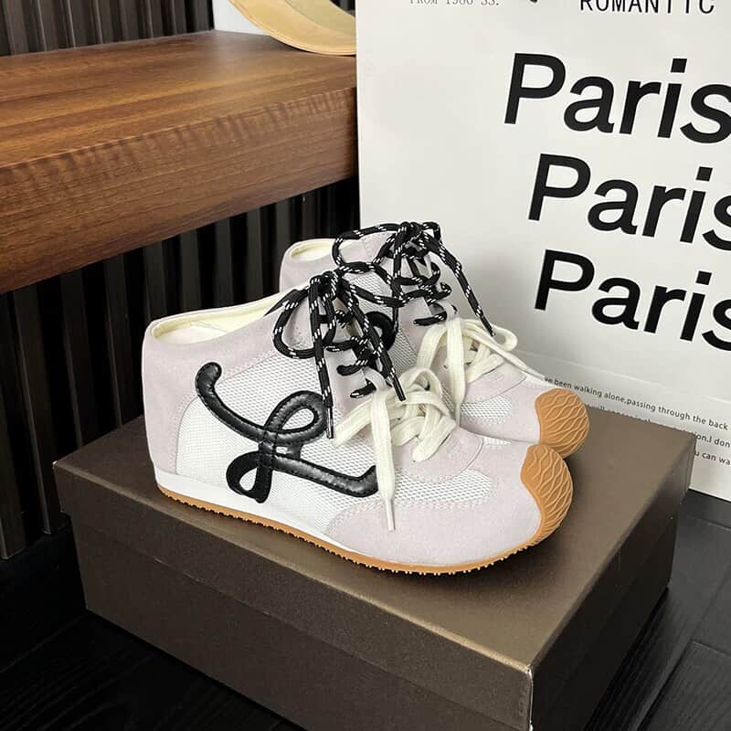 White sneakers with black laces on a brown box,