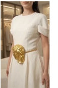 Model wearing gold sculpted buckle belt with ivory dress — cropped view