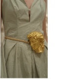 Close-up of gold sculpted buckle belt on sage green dress