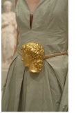 Detail of gold sculpted buckle belt on sage green dress