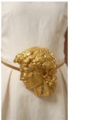 Close-up of gold sculpted buckle belt on ivory dress