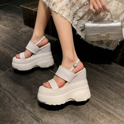 White platform sandals worn by a person on a dark floor.