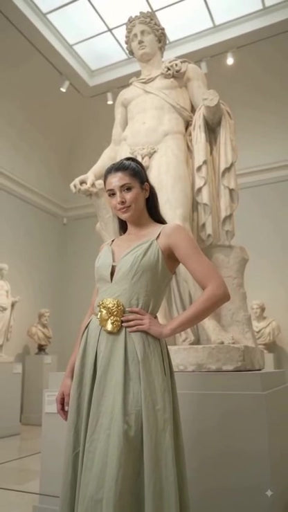 Model in sage green dress wearing gold sculpted face buckle belt — full length