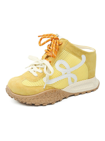 Yellow sneaker with orange laces on a white background